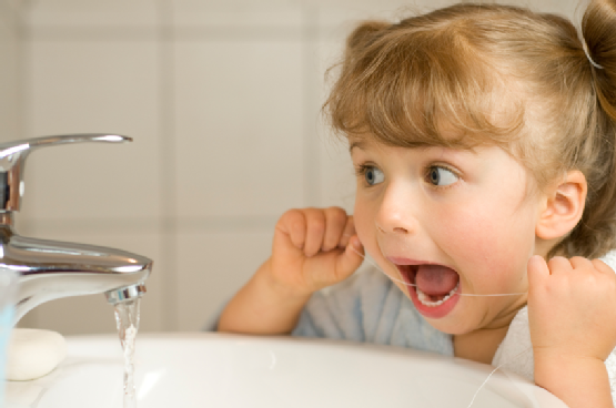 Cute girl cleaning teeth by floss