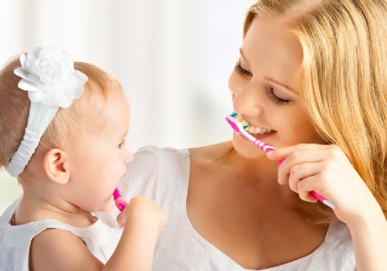 mother and daughter baby girl brushing their teeth together